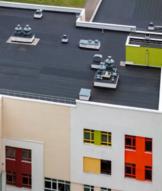 Top view flat roof with air conditioners and hydro insulation membranes on top of a modern apartment yellow green red building.