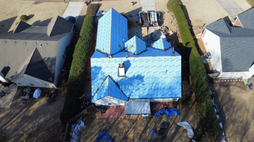 Residential roof showing blue tarp protection and ongoing repair work.