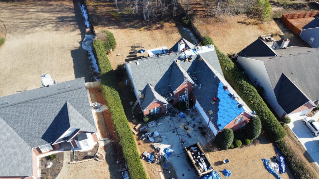 Aerial view of a roofing crew installing new shingles on a residential property.
