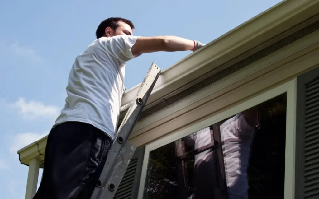 Homeowner inspecting gutter seams and downspout during spring gutter cleaning at Greater Atlanta, GA home