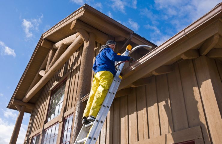 Professional gutter cleaning technician working on two-story home in Greater Atlanta, GA during spring maintenance