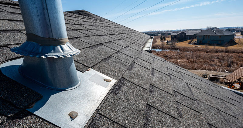 Newly installed step flashing along a brick chimney on a residential shingle roof