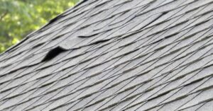 Close-up view of missing and slipped shingles on a residential asphalt roof
